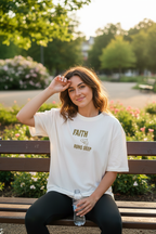 Frau macht Pause nach Workout und trägt weißes Faith Runs Deep Oversized T-Shirt